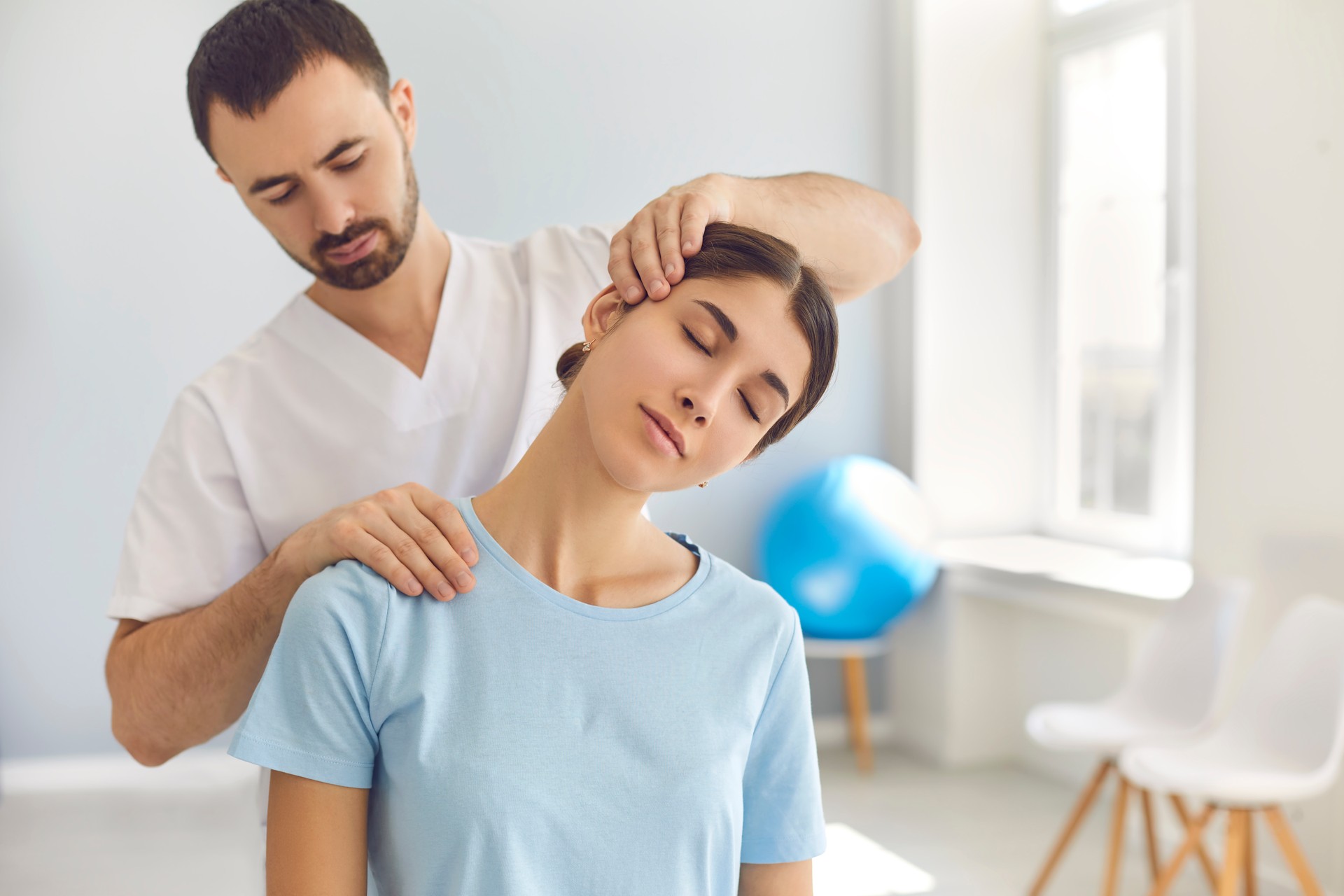 Licensed chiropractor doing neck adjustment to female patient in modern medical office